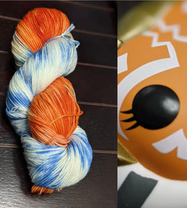 orange, blue and white variegated yarn on a cut screen with a funko pop